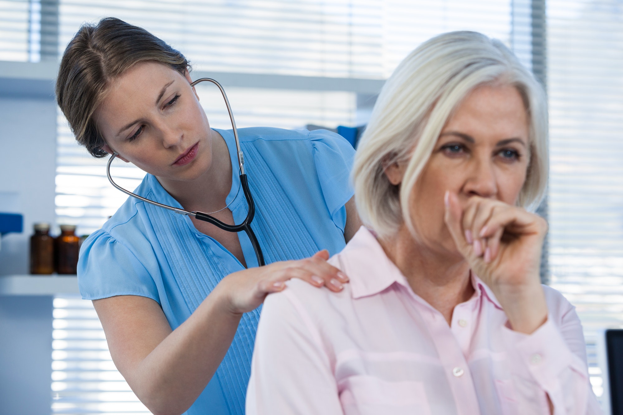 Doctor examining coughing patient