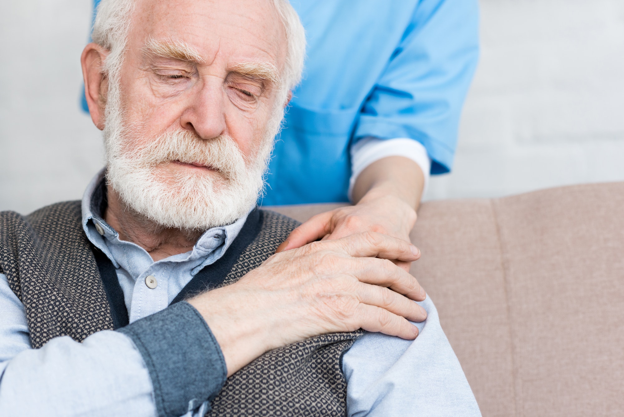 Nurse putting hand on sad senior man