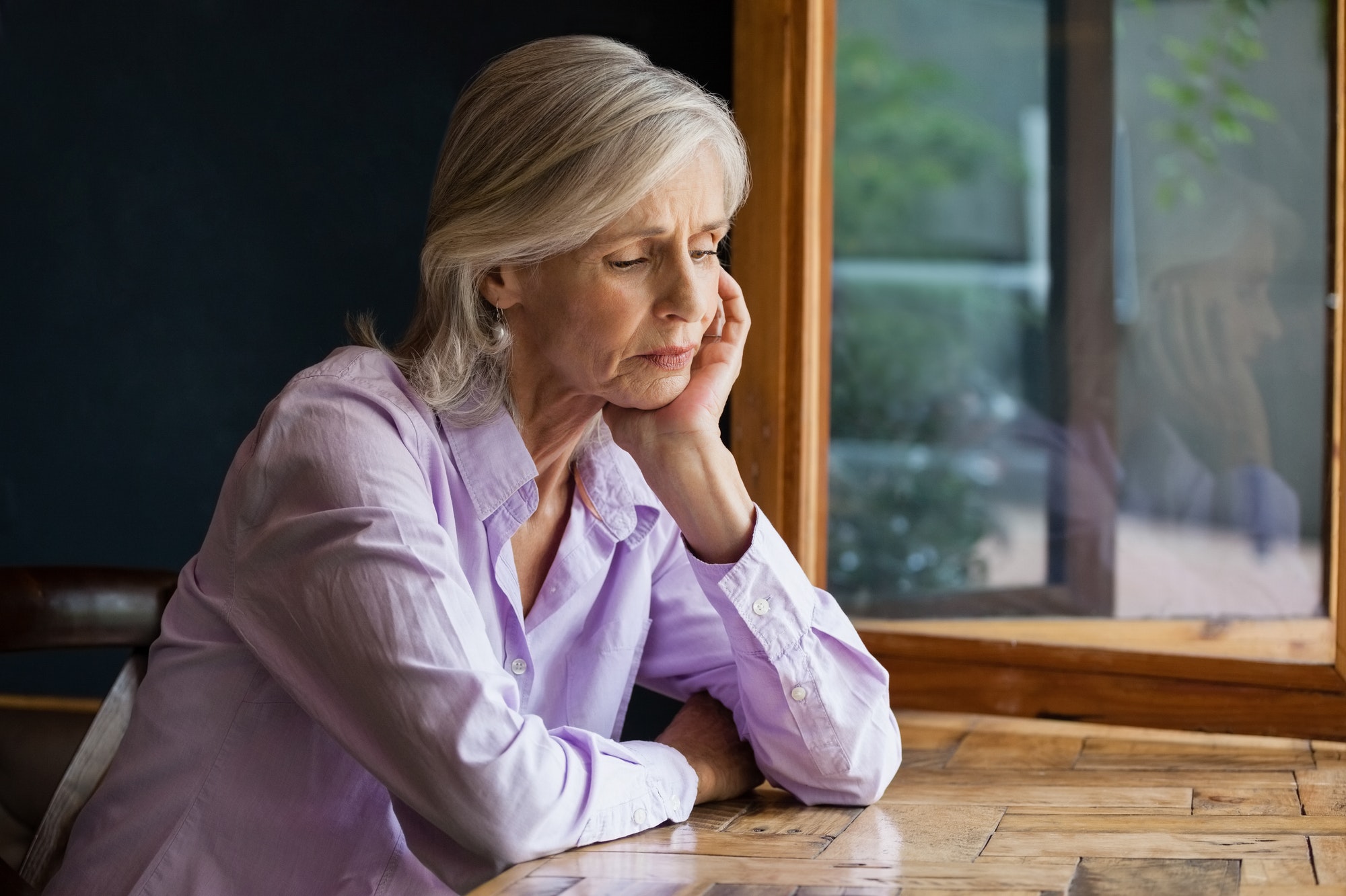 Sad senior woman sitting at table