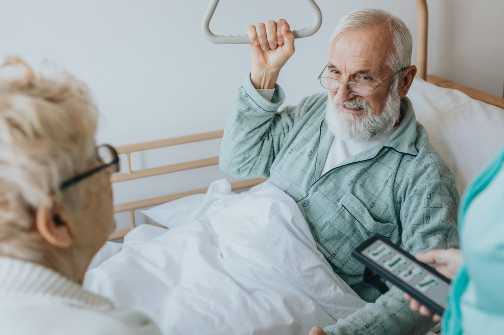 Senior patient gets up from the hospital bed by helping himself with a special handle